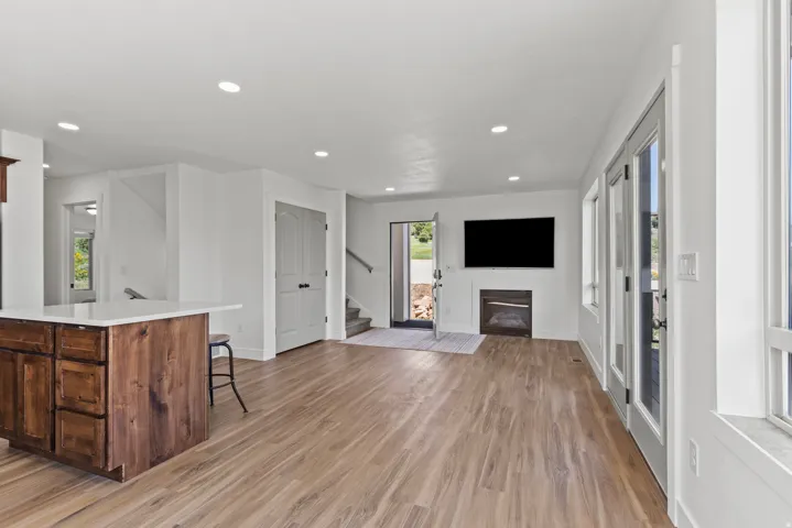 Unfurnished living room with light wood-style flooring, a glass covered fireplace, and recessed lighting