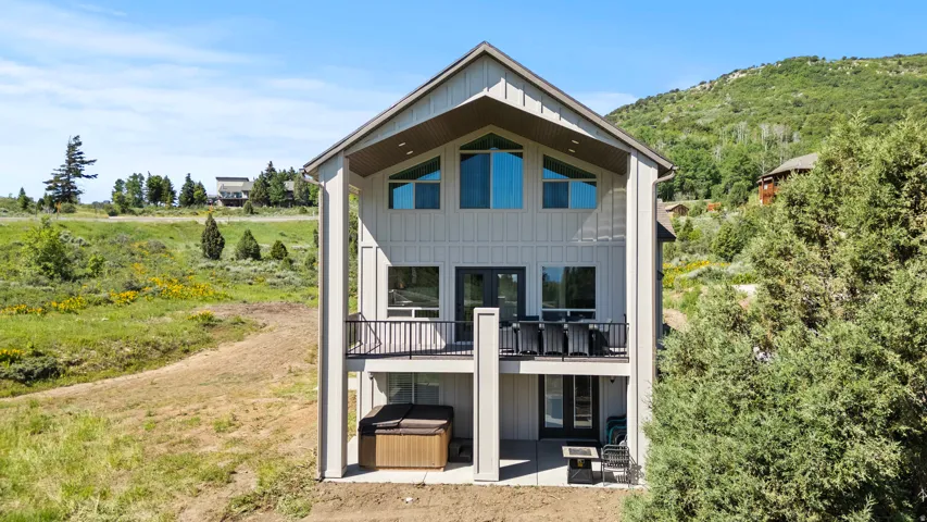 Back of house featuring a hot tub, a patio, board and batten siding, and french doors