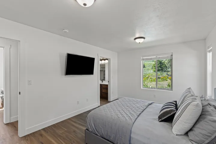 Bedroom featuring dark wood-type flooring and ensuite bathroom