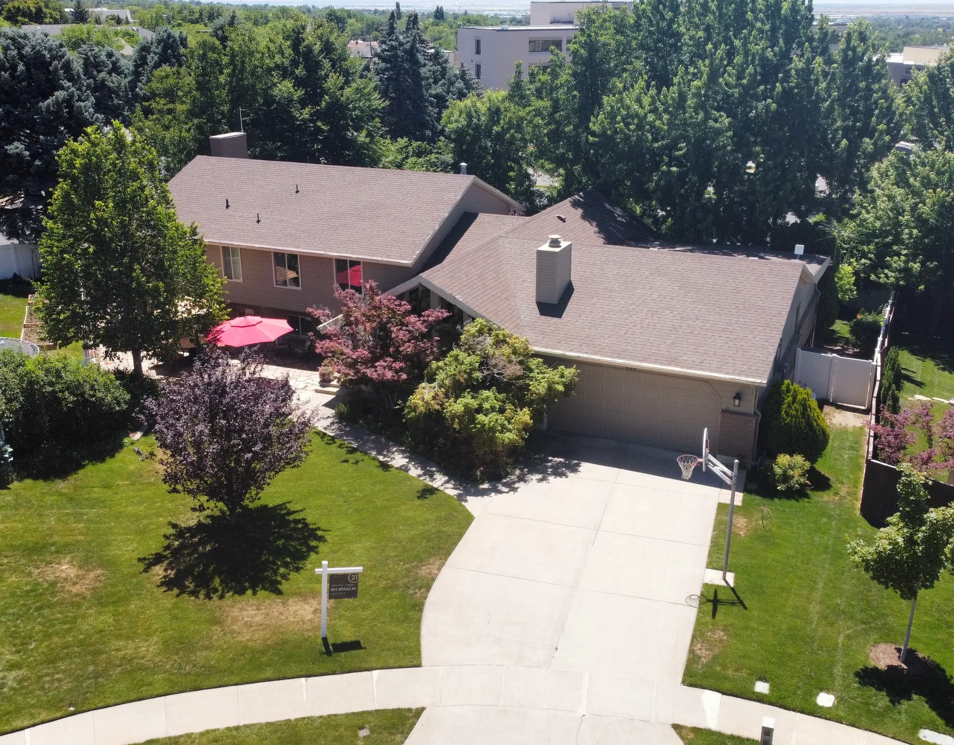 Expansive residential property featuring a broad driveway, attached garage, and a large paved patio area