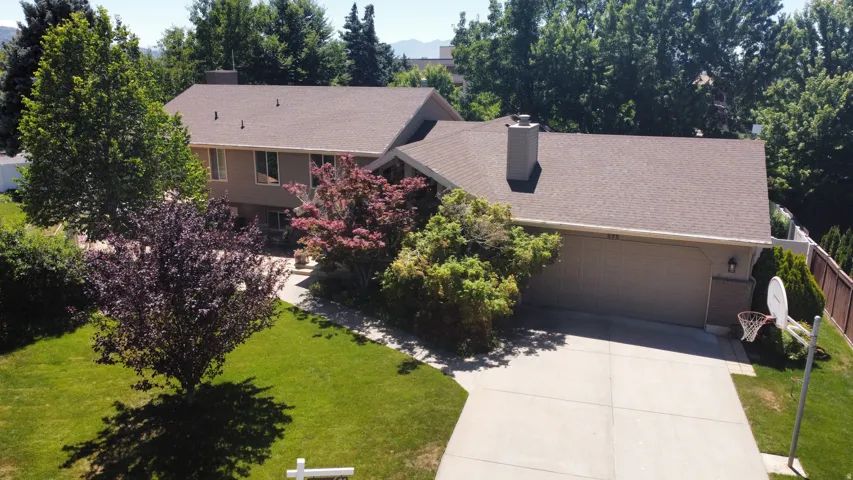Split-level residence featuring a two-car garage, concrete driveway, and a basketball hoop