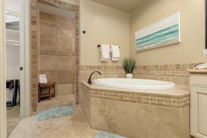 Primary bathroom with a garden tub, vanity, walk in shower, and light tile patterned floors