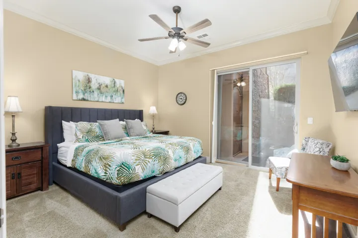 Primary bedroom featuring carpet floors, ornamental molding, access to exterior, and a ceiling fan
