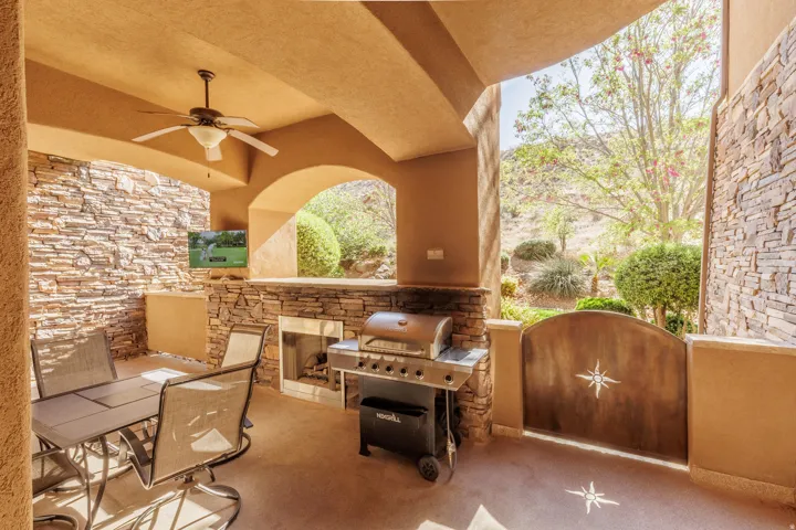 View of patio with a ceiling fan, a gate, a fireplace, a TV, and area for grilling
