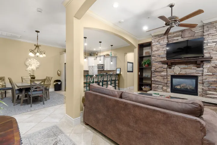 Living area with ornamental molding, a fireplace, light tile patterned floors, a ceiling fan, and hanging lights