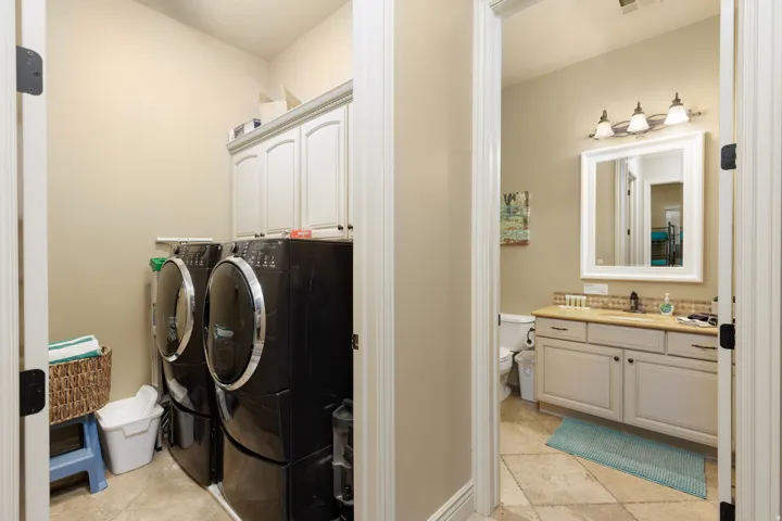 Laundry area featuring washer and clothes dryer, cabinet space, and light tile patterned floors