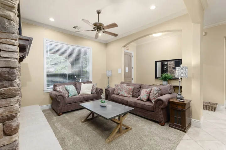Living room featuring crown molding, arched walkways, a ceiling fan, recessed lighting, and light tile patterned floors