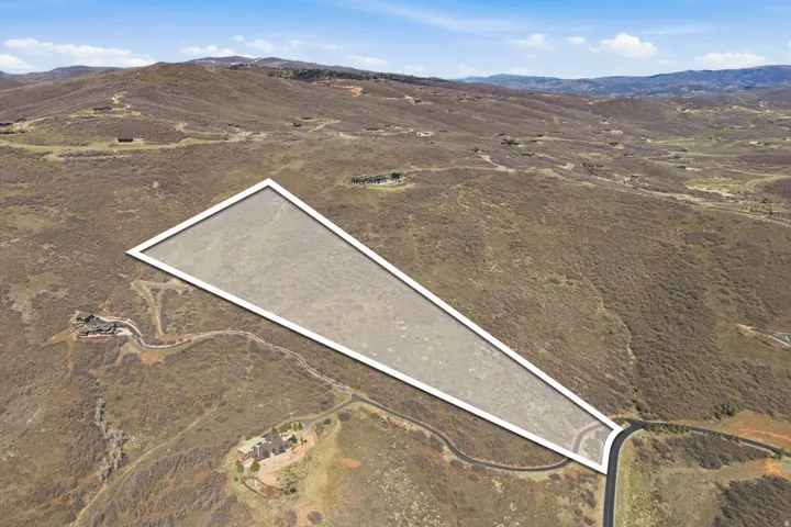 Expansive parcel featuring a defined boundary, surrounding natural terrain, and access to a paved road