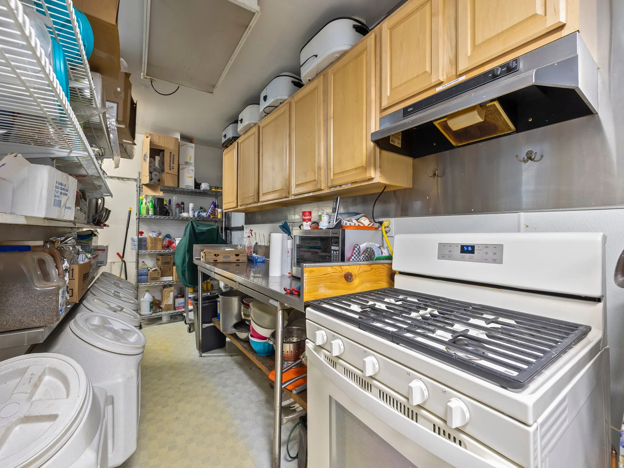 Kitchen featuring white gas range oven, stainless steel microwave, and light wood finish cabinetry