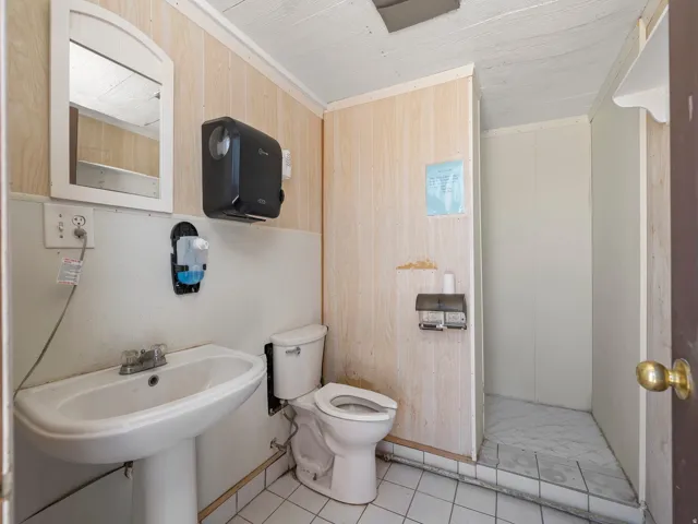Bathroom featuring wooden walls, ornamental molding, and light tile patterned floors