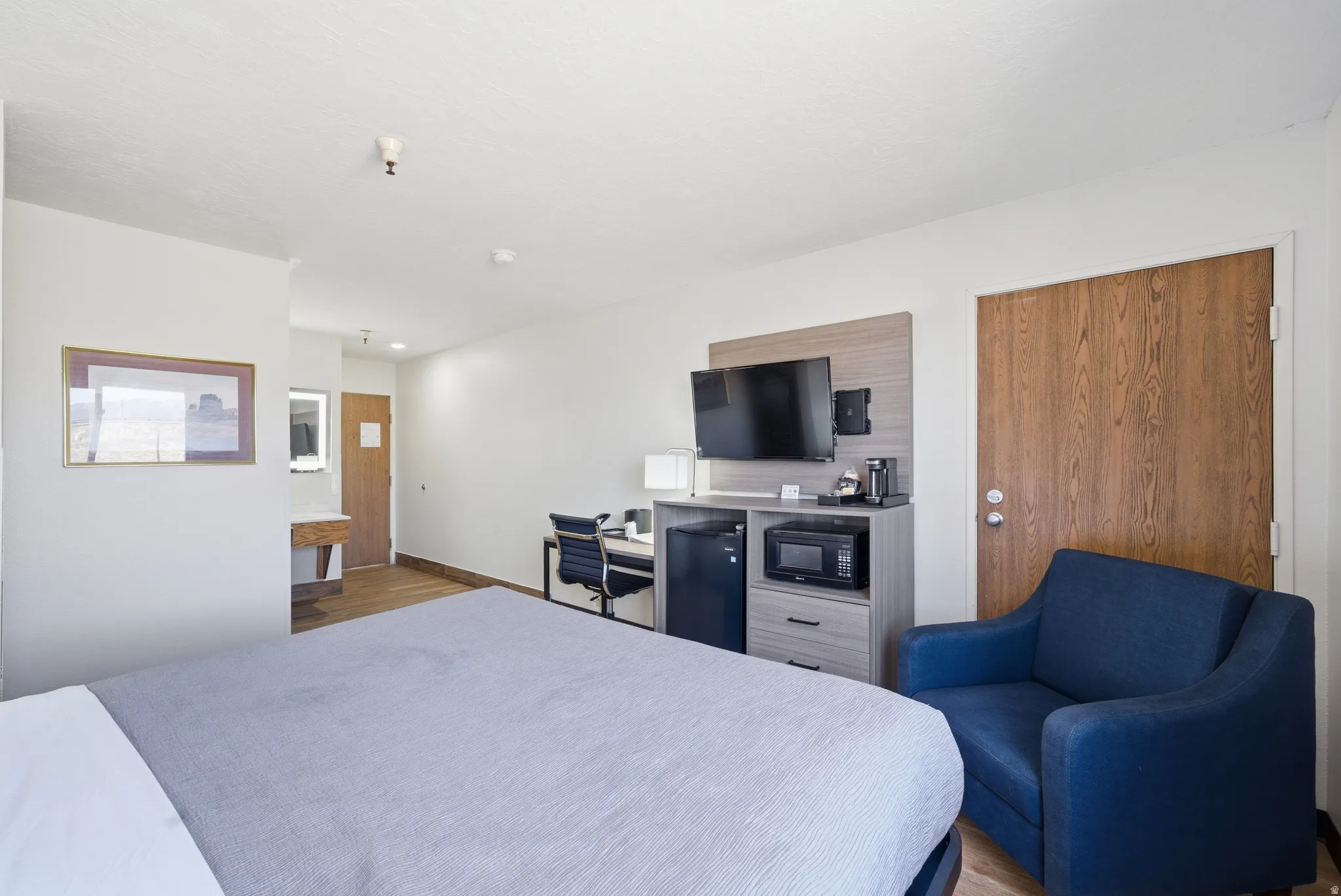 Bedroom with black fridge and light wood-style flooring