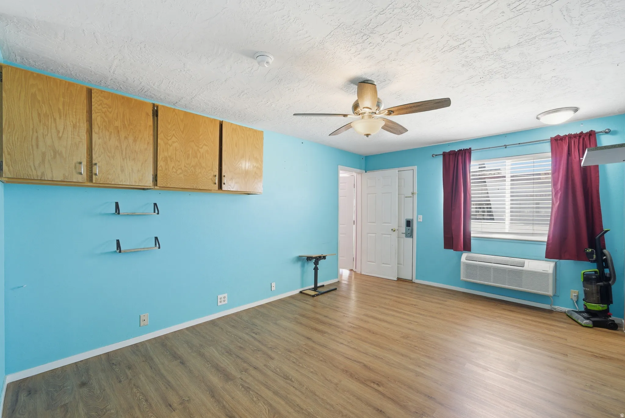 Empty room featuring wood finished floors, a ceiling fan, and a textured ceiling