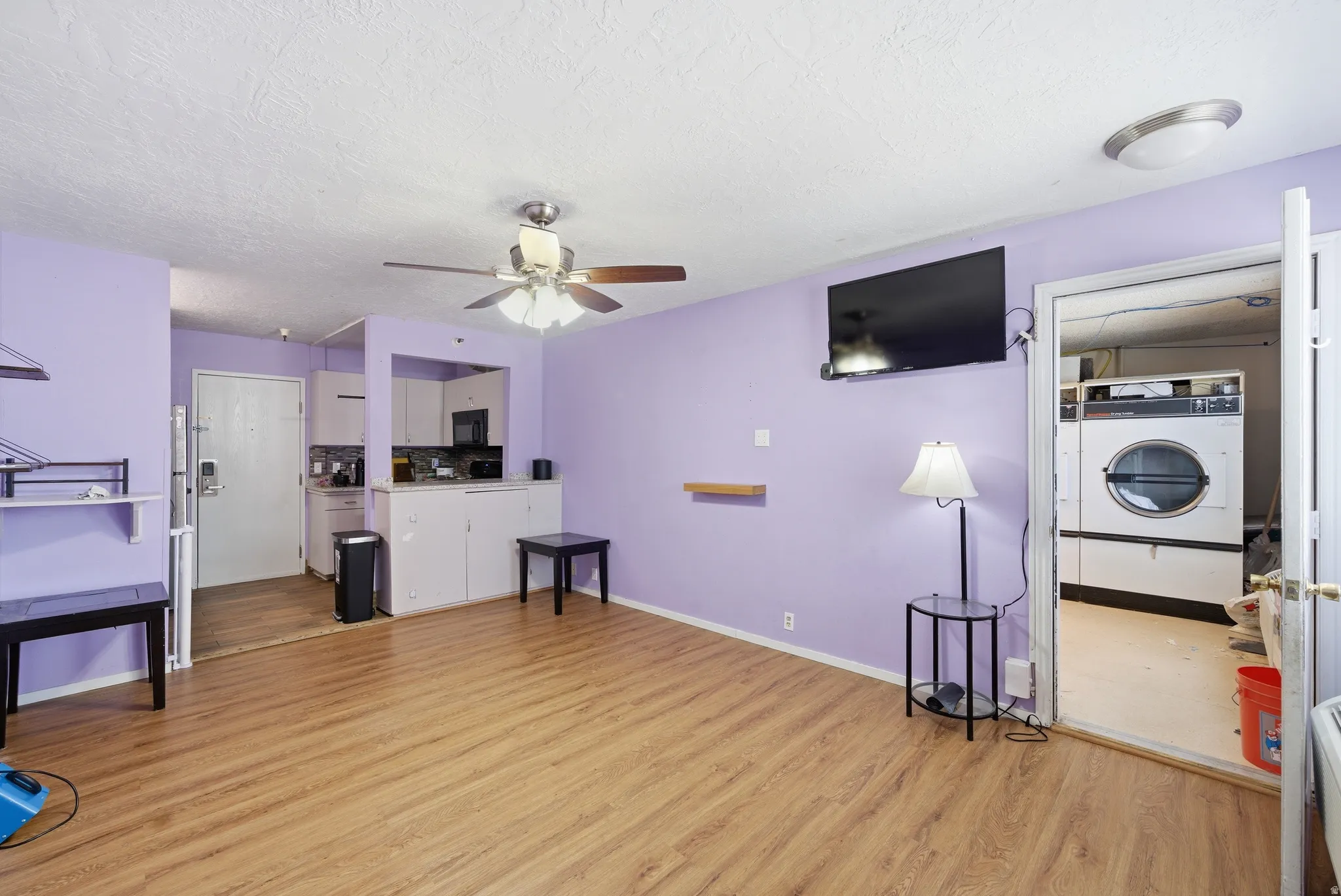 Living area with light wood-style floors, a ceiling fan, washer / dryer, and a textured ceiling