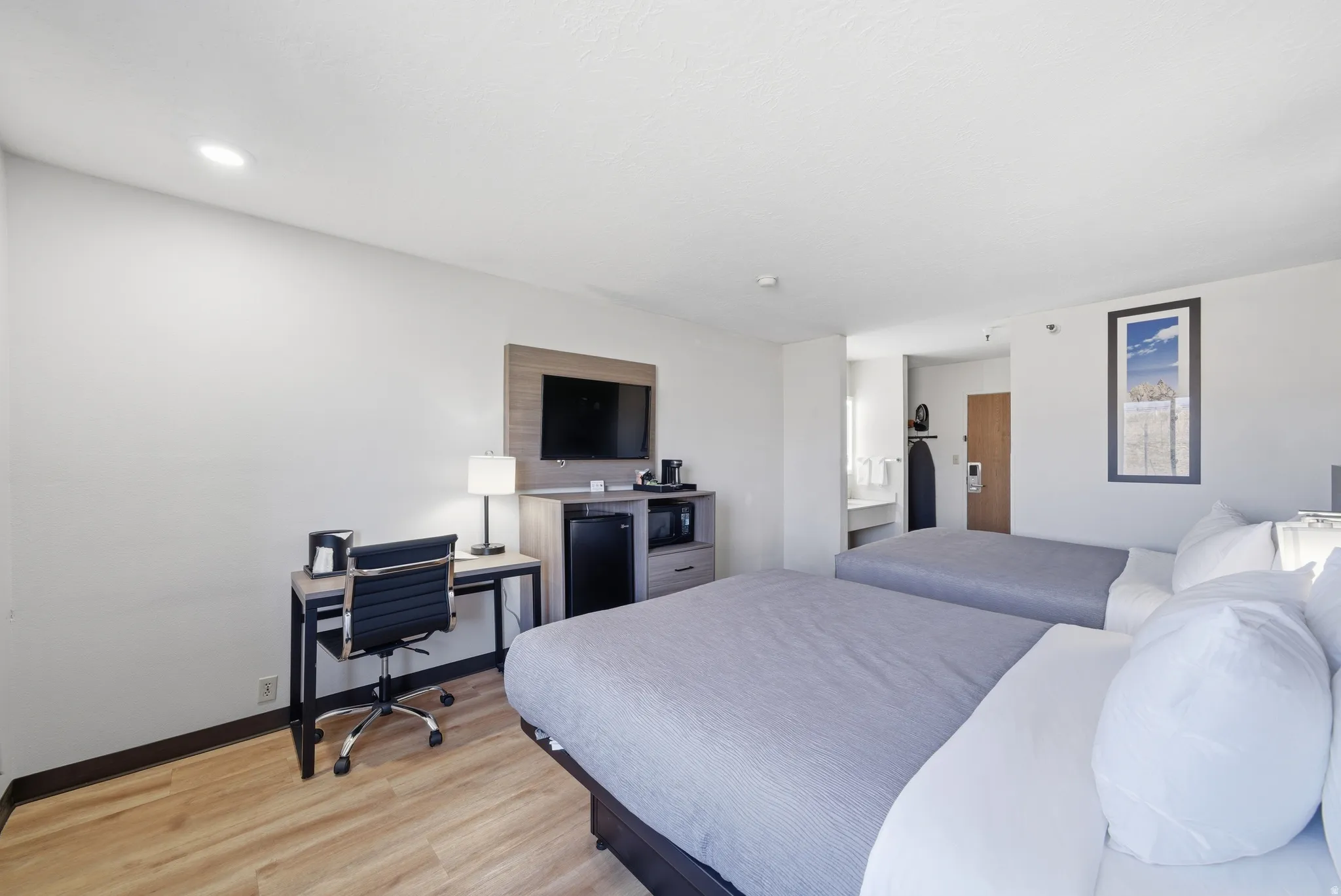 Bedroom with light wood-type flooring and black refrigerator