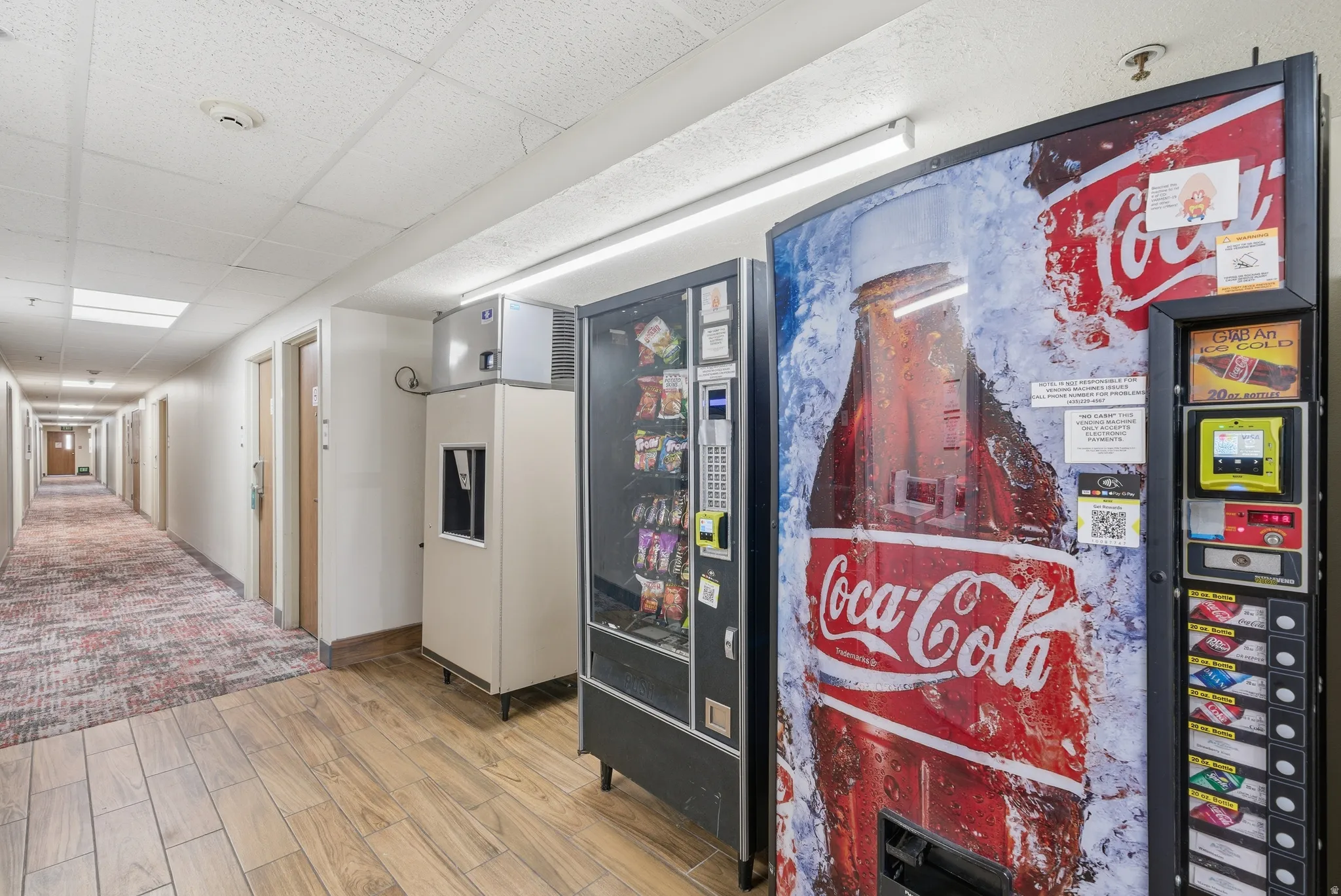 Detailed view of a paneled ceiling, wood finish floors, and refrigerator with ice dispenser