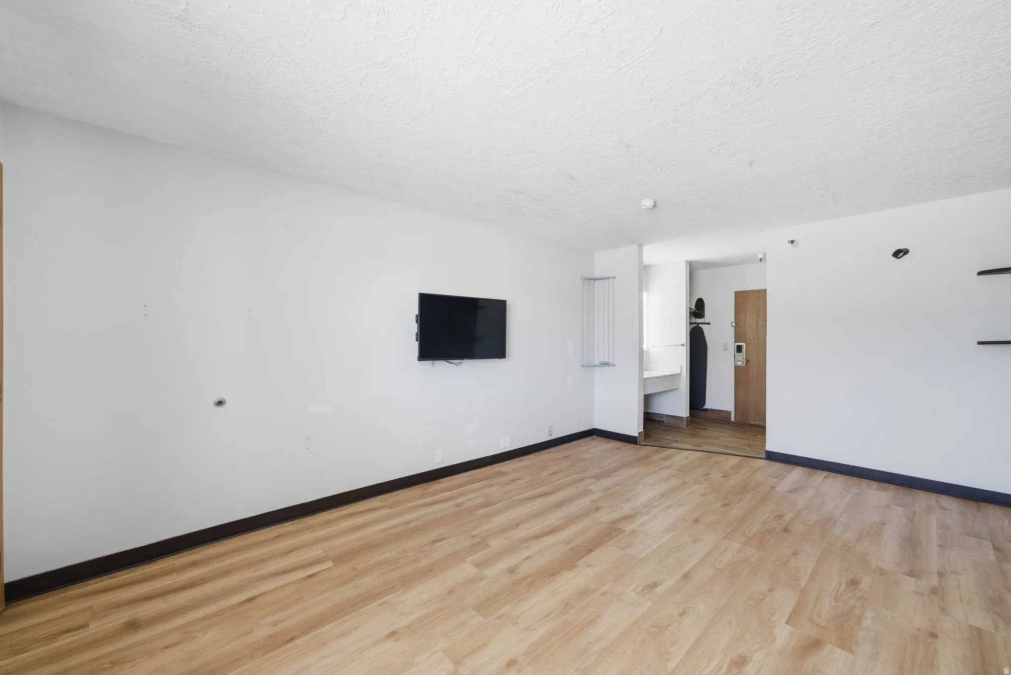 Unfurnished room featuring light wood-style flooring and a textured ceiling