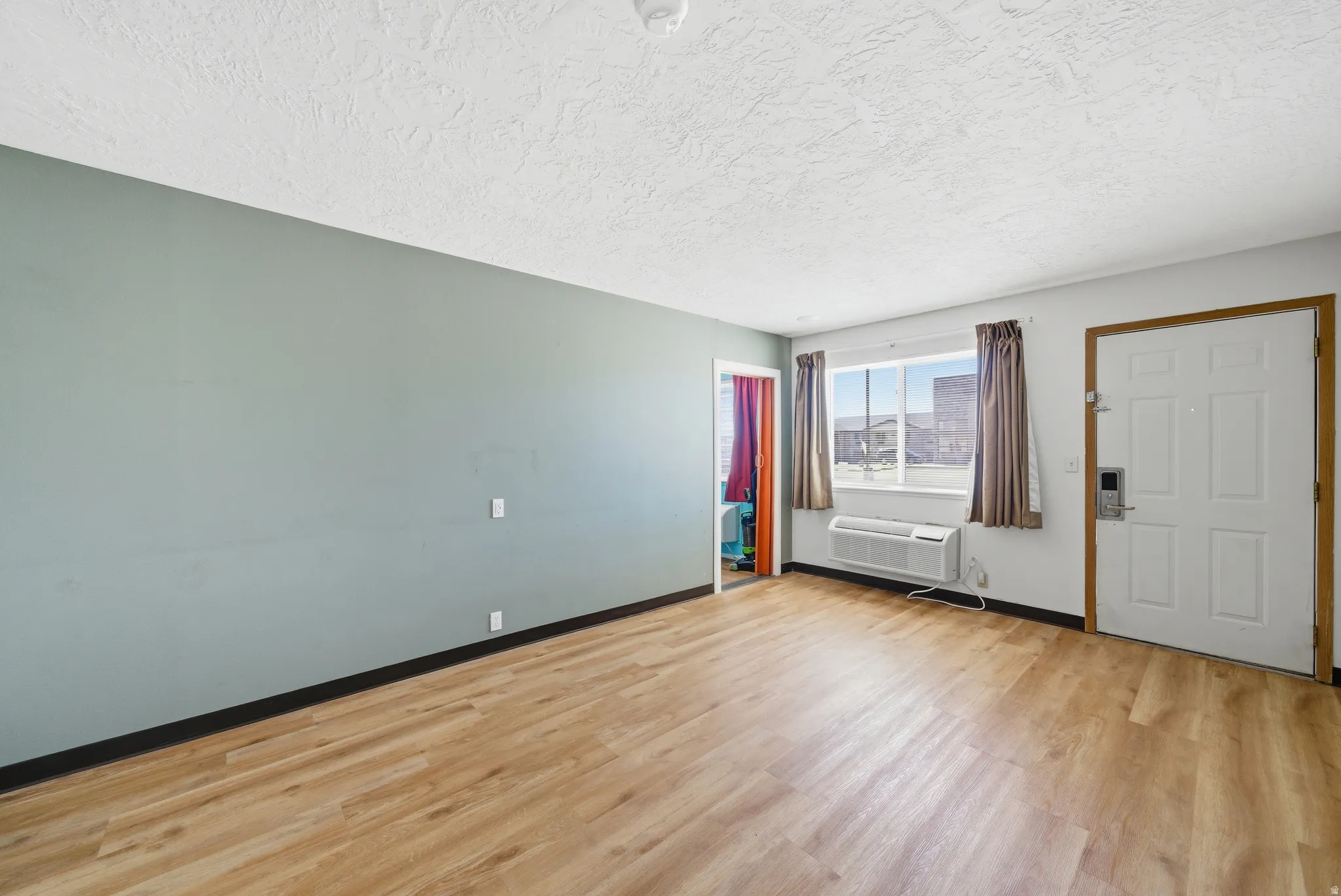 Empty room with light wood-style flooring and a textured ceiling