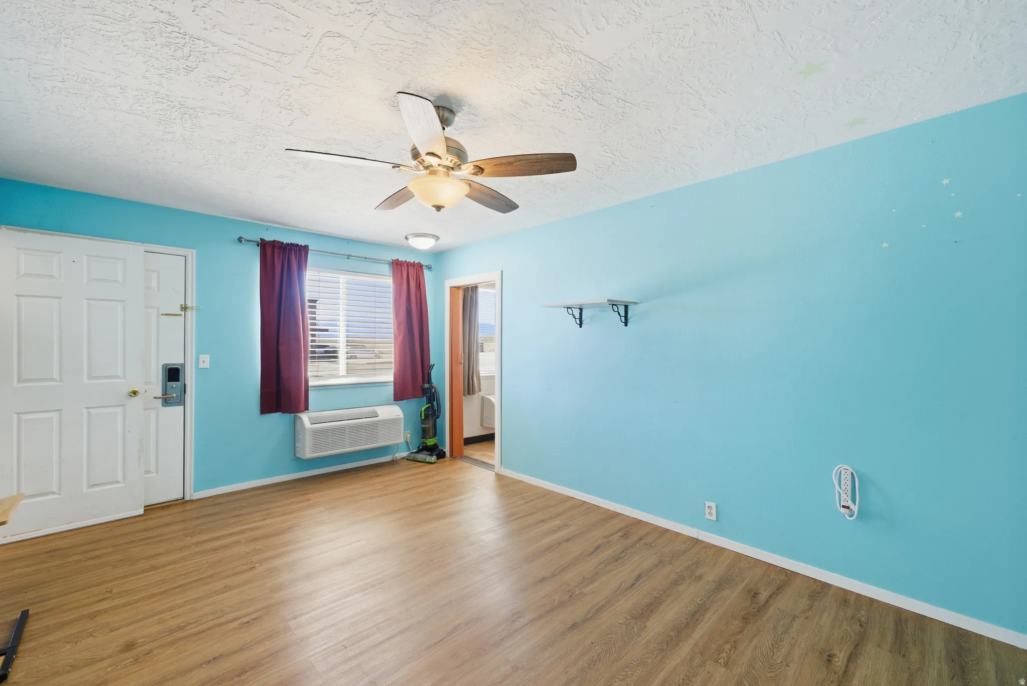 Entryway with wood finished floors, a textured ceiling, and a ceiling fan