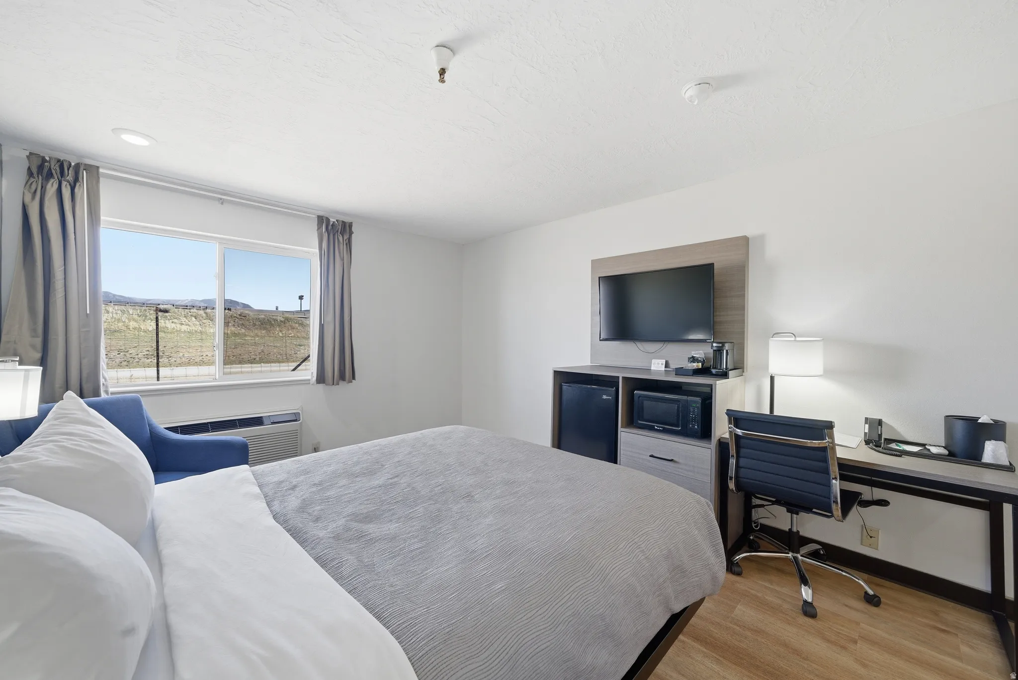 Bedroom with fridge, light wood-type flooring, and a desk