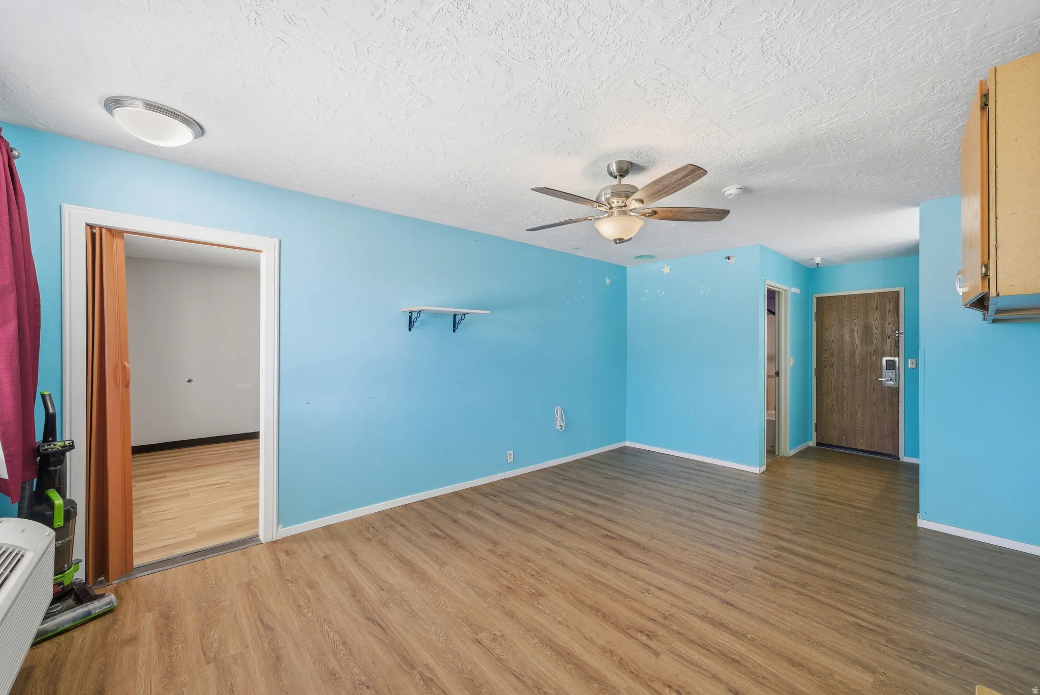 Unfurnished living room with wood finished floors, a ceiling fan, and a textured ceiling