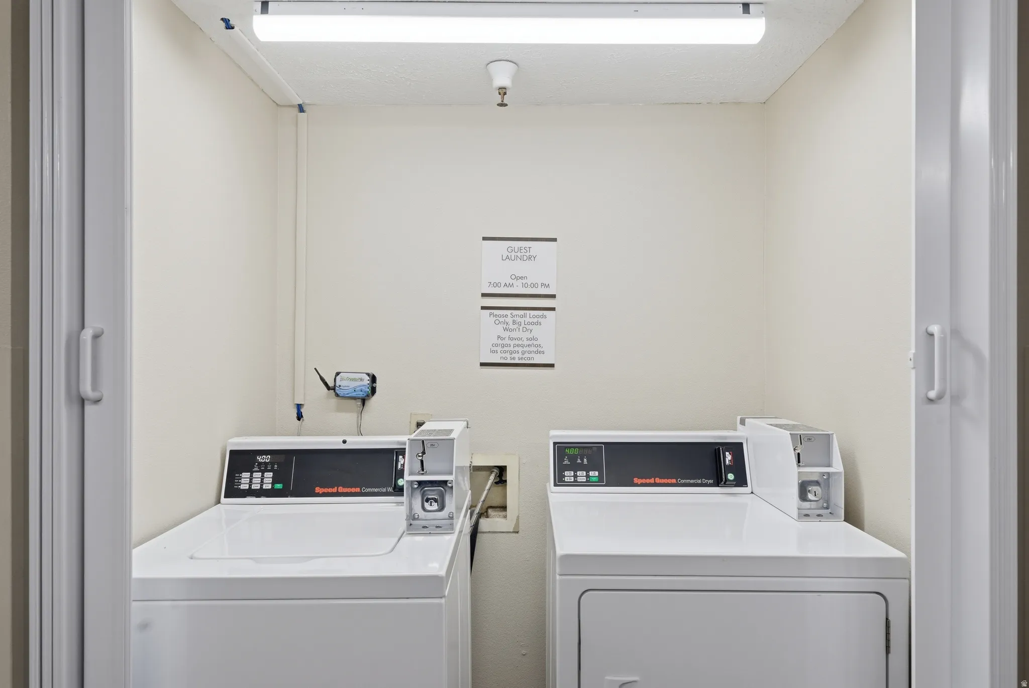 Community laundry room with washing machine and clothes dryer