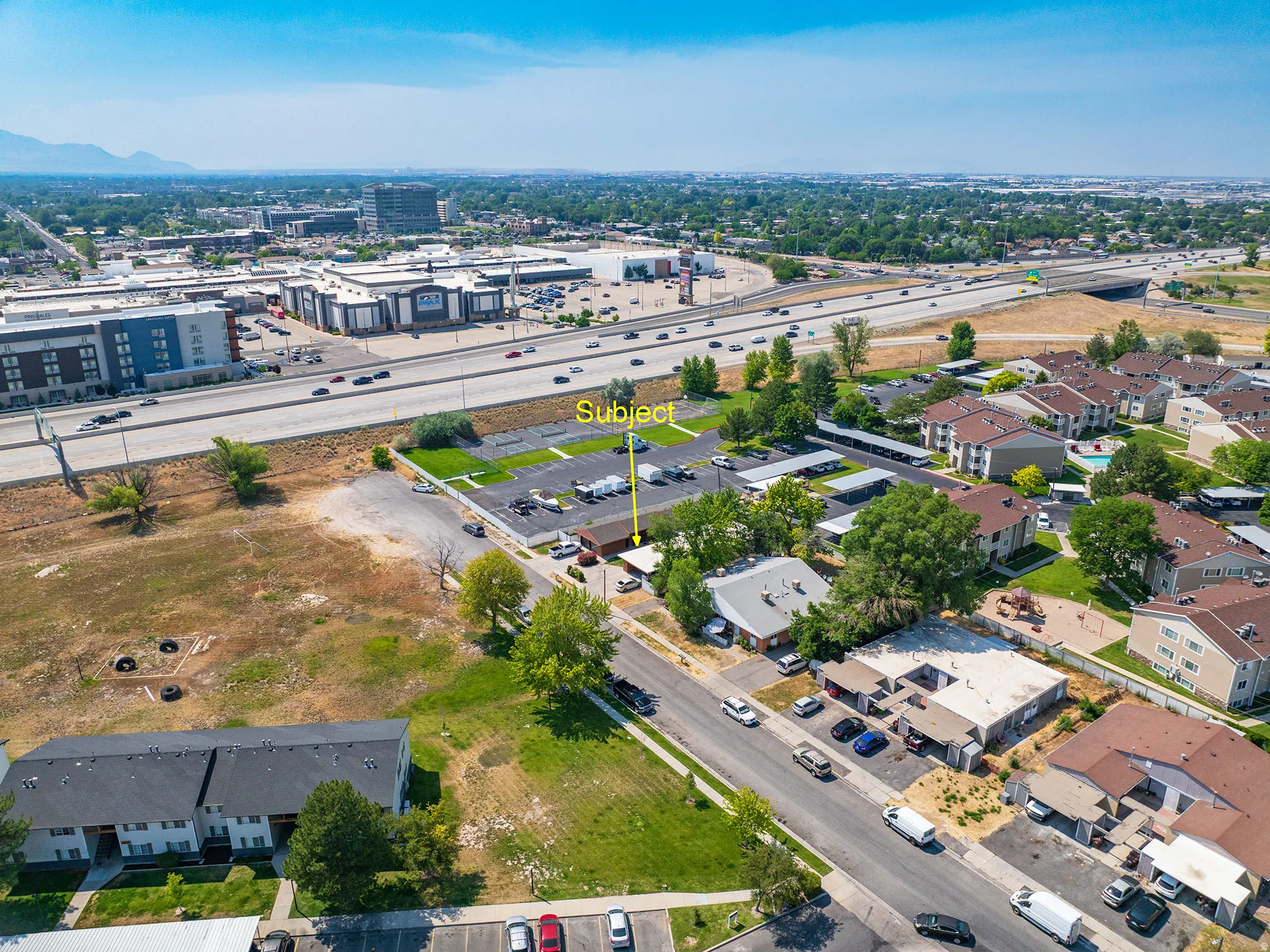 Aerial perspective showcasing a single-story building with a light-colored roof, surrounded by paved parking areas