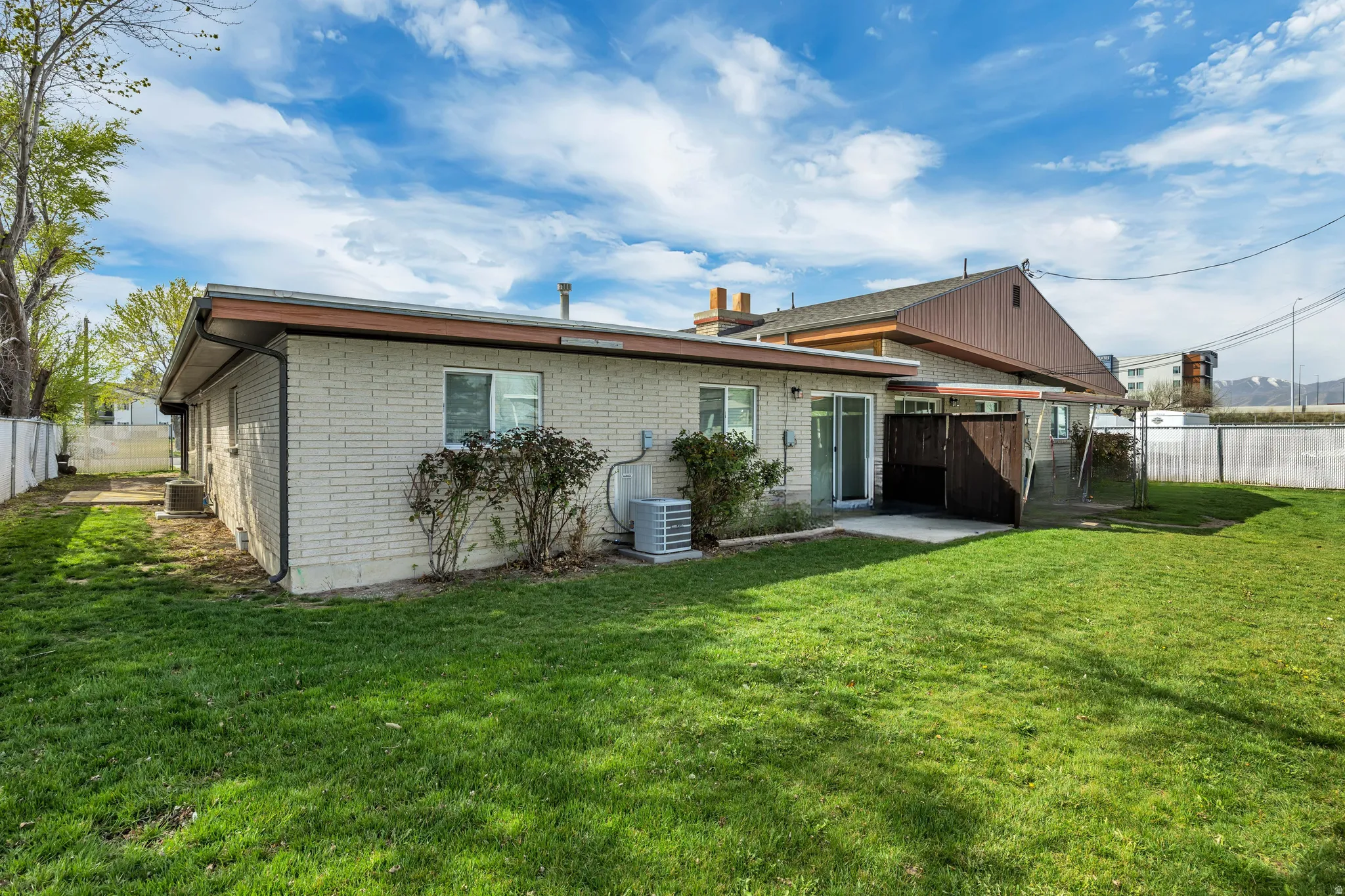Back of house with a fenced backyard, brick siding, and a patio area