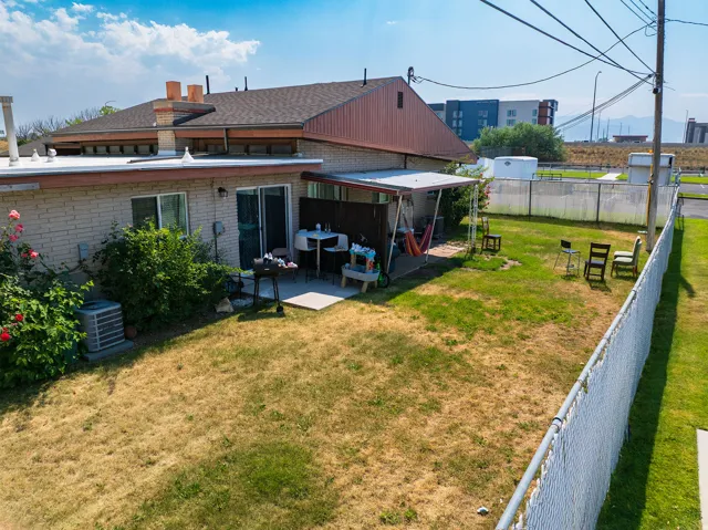 Rear exterior featuring a covered patio, sliding glass door entry, and a chain-link fence