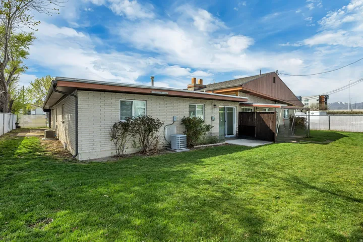 Back of house with a fenced backyard, brick siding, and a patio area