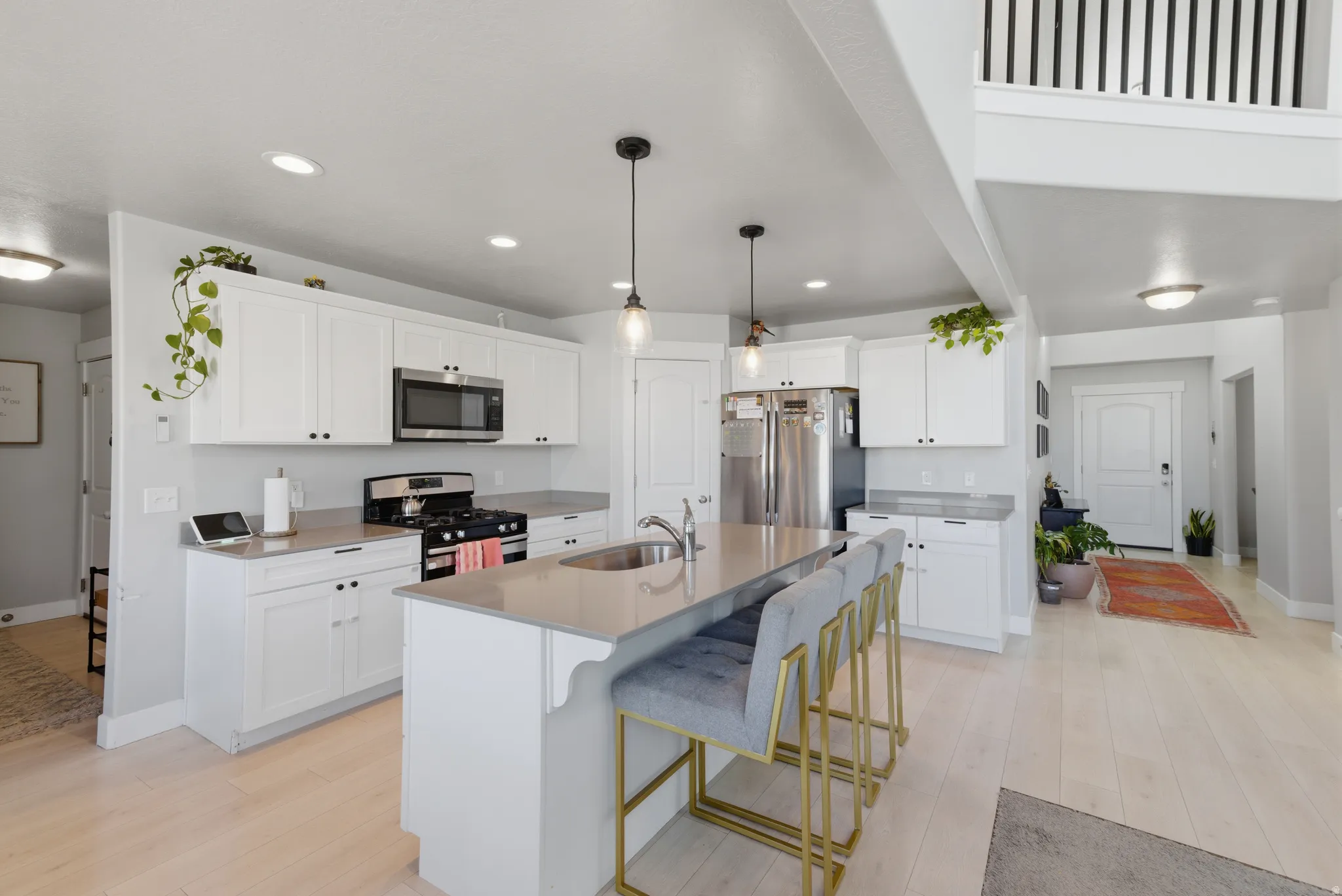 Kitchen with white cabinetry, stainless steel appliances, light wood-style floors, a center island with sink, and a kitchen breakfast bar