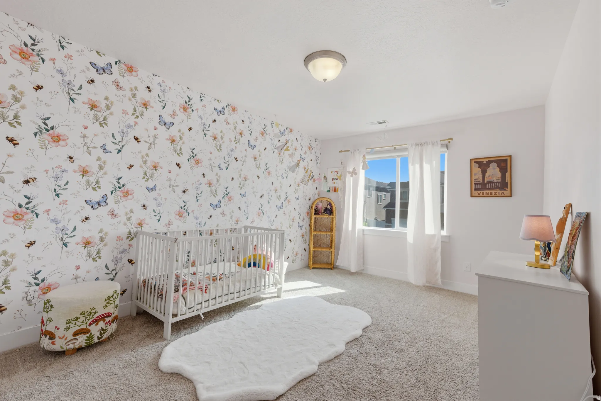 Bedroom with wallpapered walls, a nursery area, and carpet