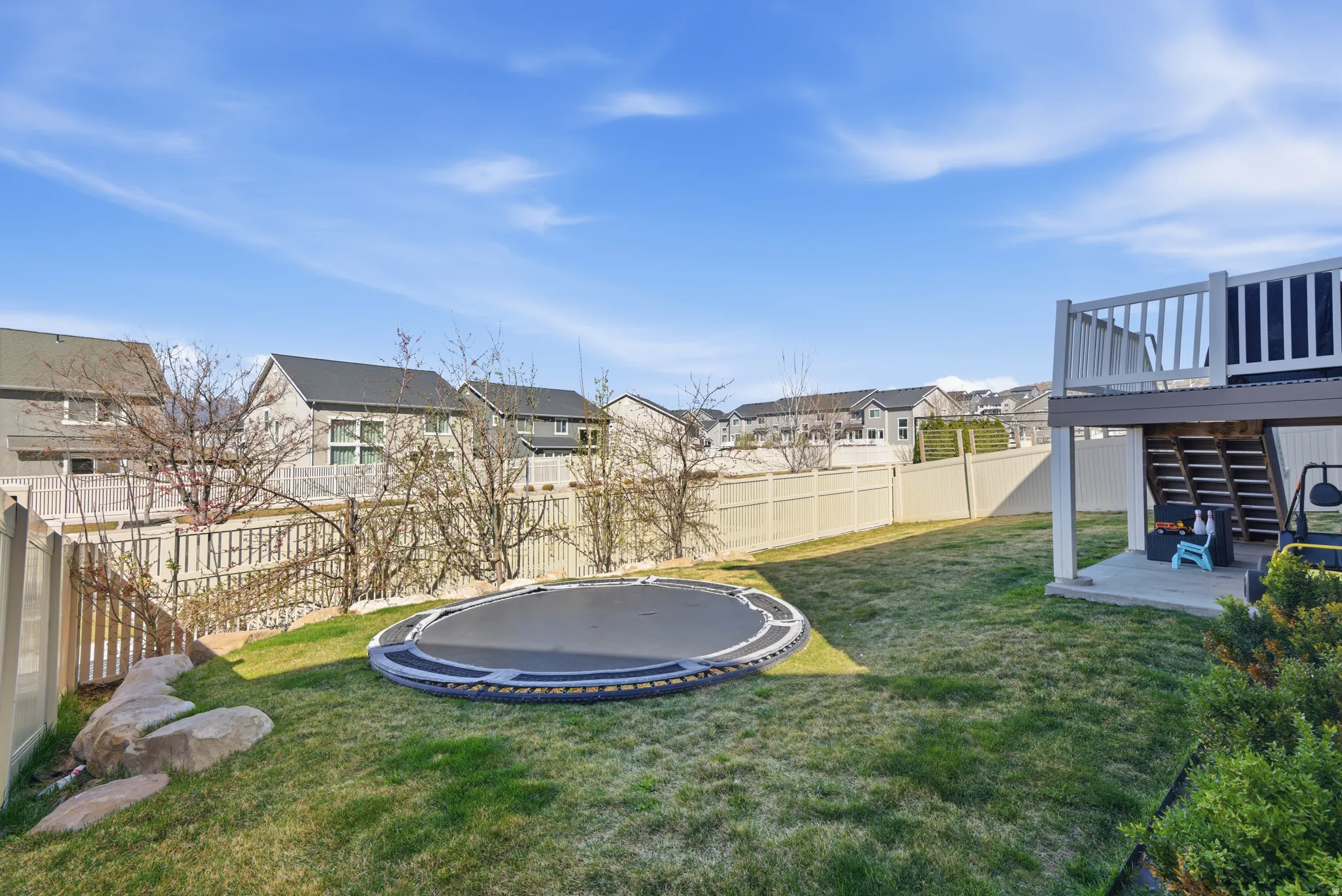 Fenced backyard featuring a trampoline, a residential view, and a patio