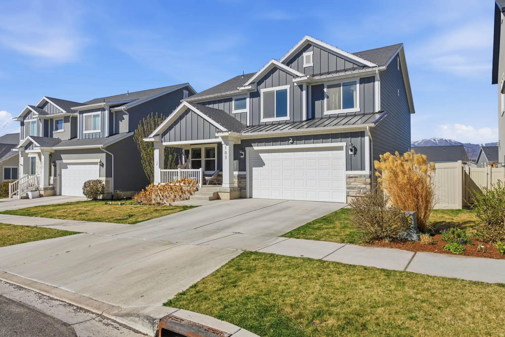 Craftsman inspired home featuring a standing seam roof, stone siding, a garage, covered porch, and board and batten siding
