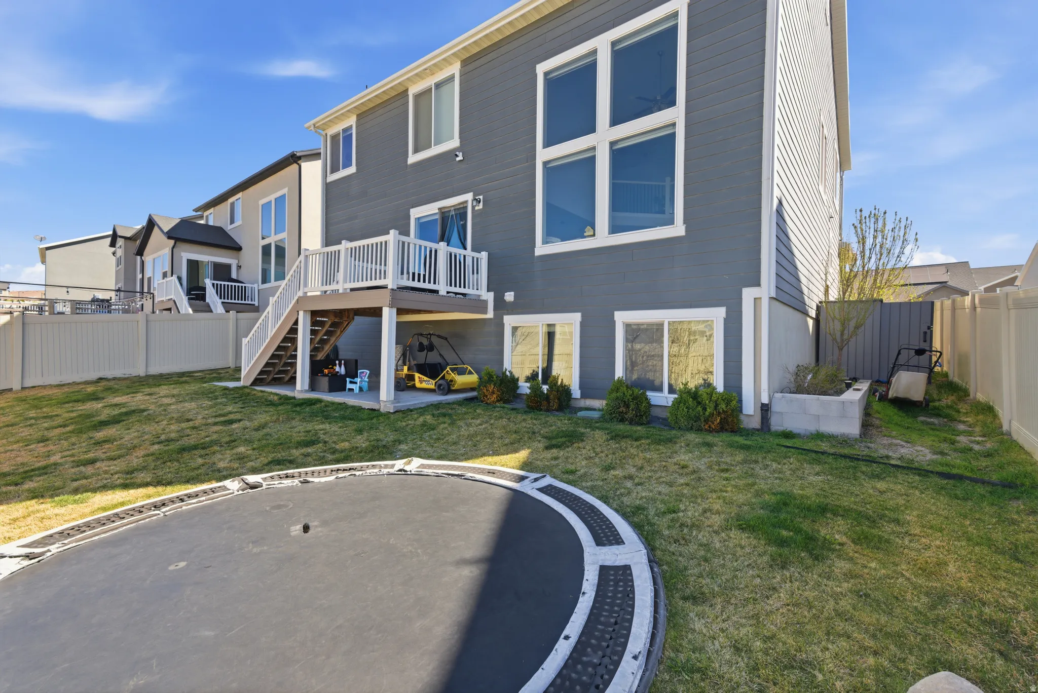 Back of property featuring a patio area, a fenced backyard, a trampoline, and a deck