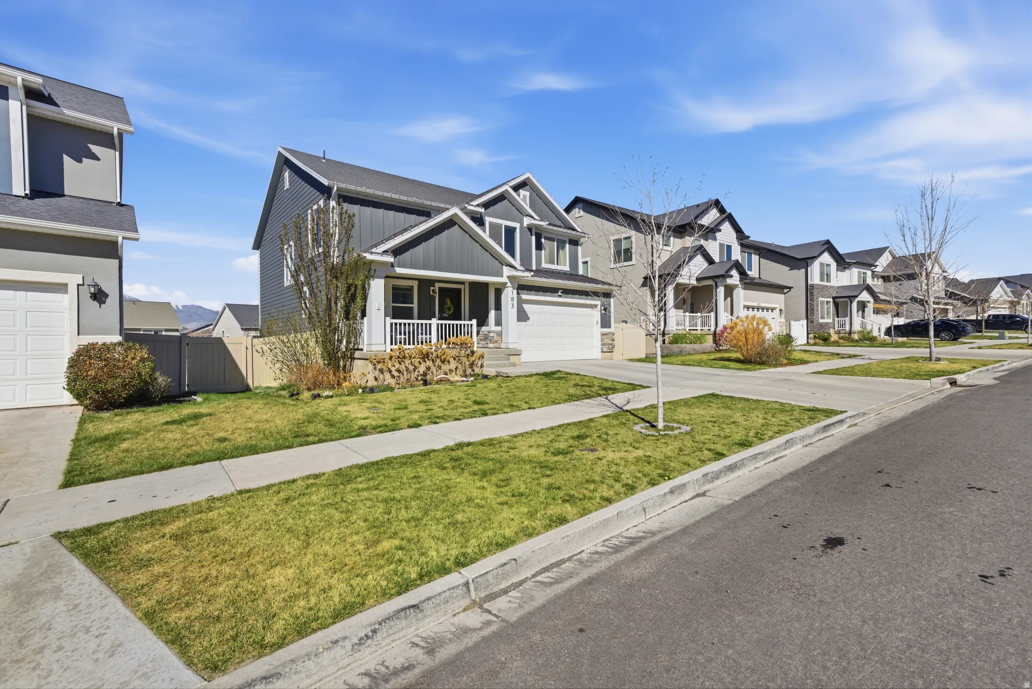View of front of property with covered porch, a residential view, board and batten siding, concrete driveway, and a garage