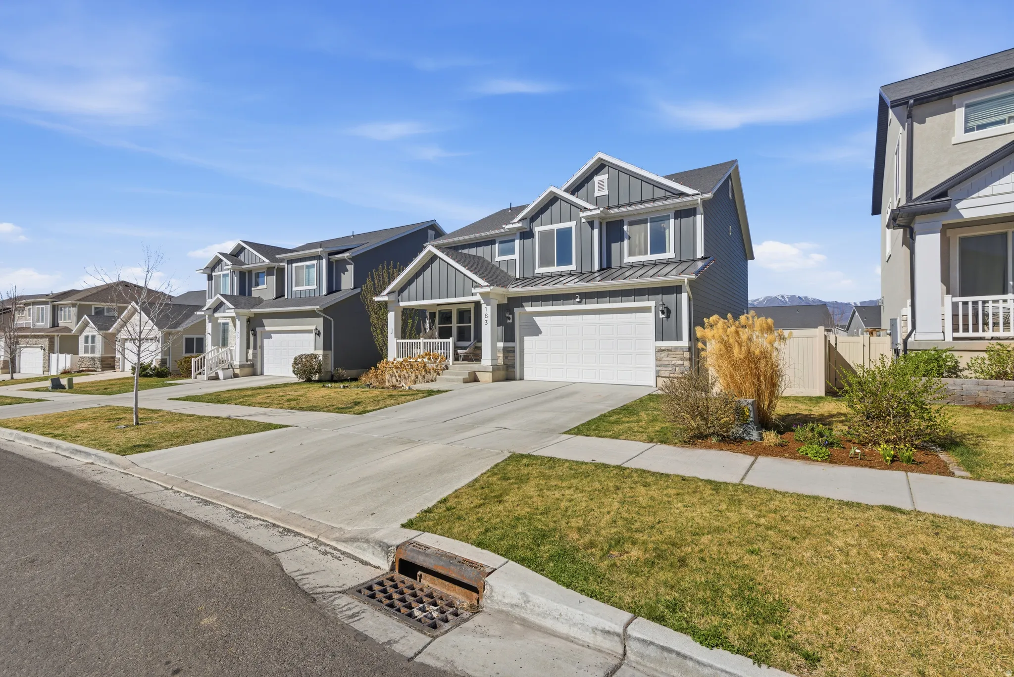 Craftsman inspired home with a garage, a standing seam roof, a residential view, concrete driveway, and board and batten siding