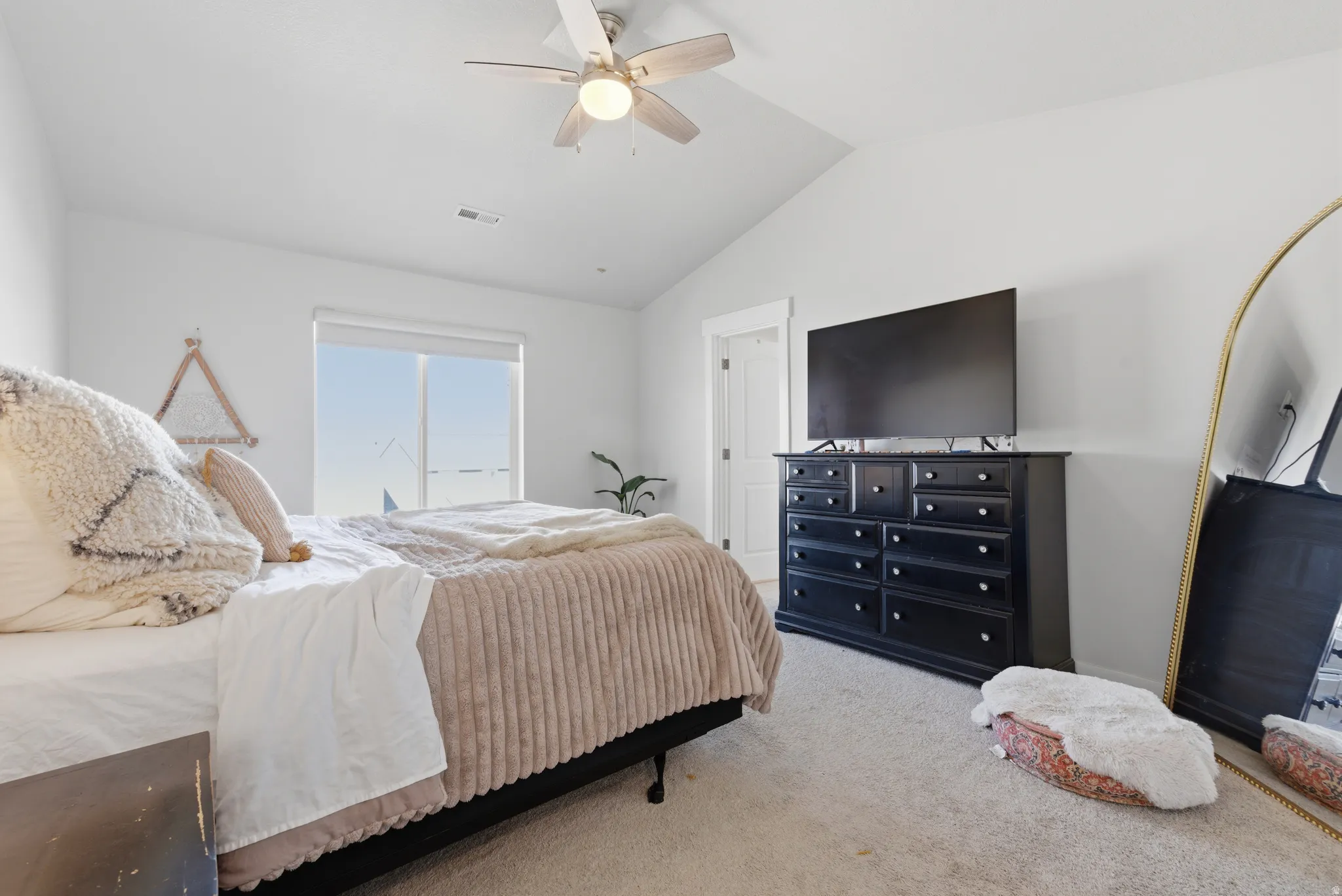 Carpeted bedroom featuring lofted ceiling and a ceiling fan