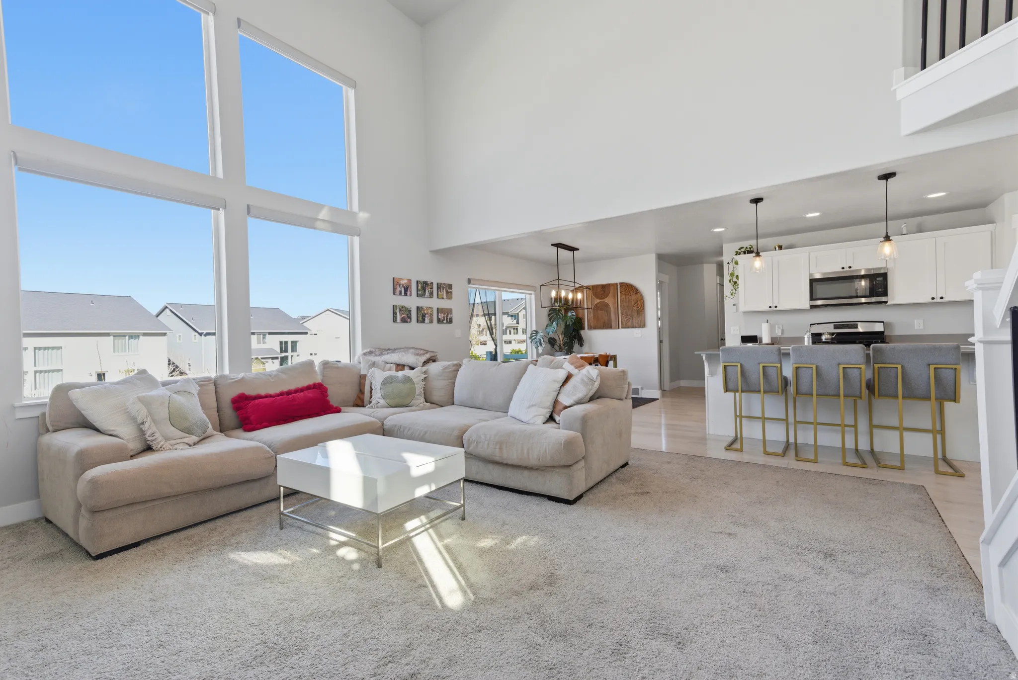 Living room featuring light carpet, a high ceiling, and a chandelier