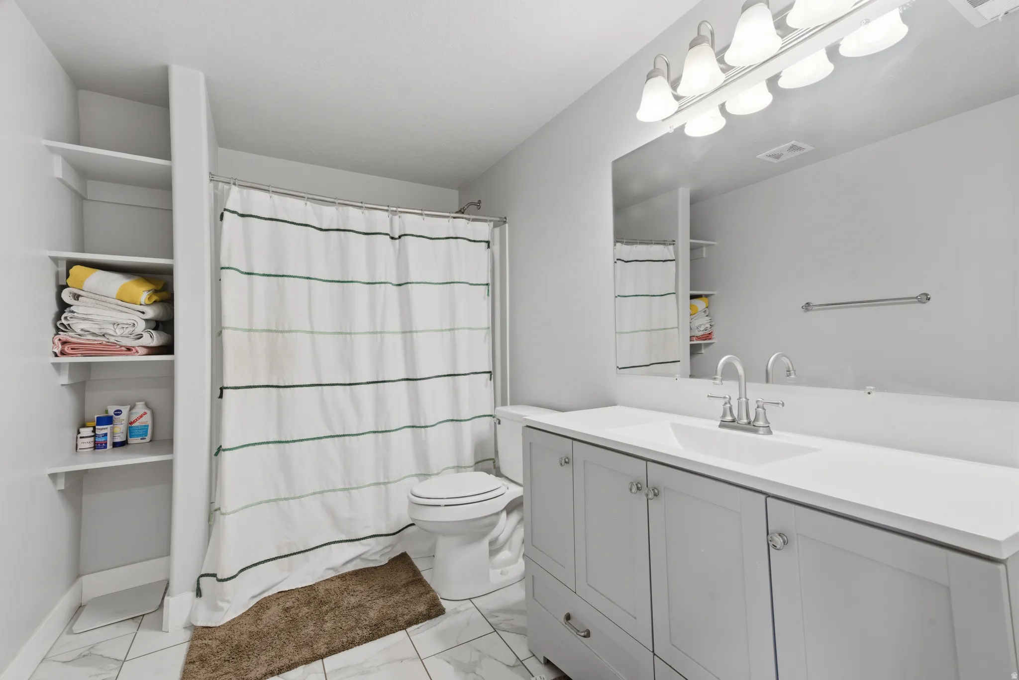 Full bathroom with curtained shower, vanity, and light marble finish flooring