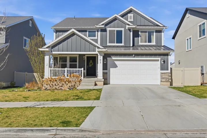 Craftsman inspired home with board and batten siding, a porch, stone siding, a standing seam roof, and concrete driveway
