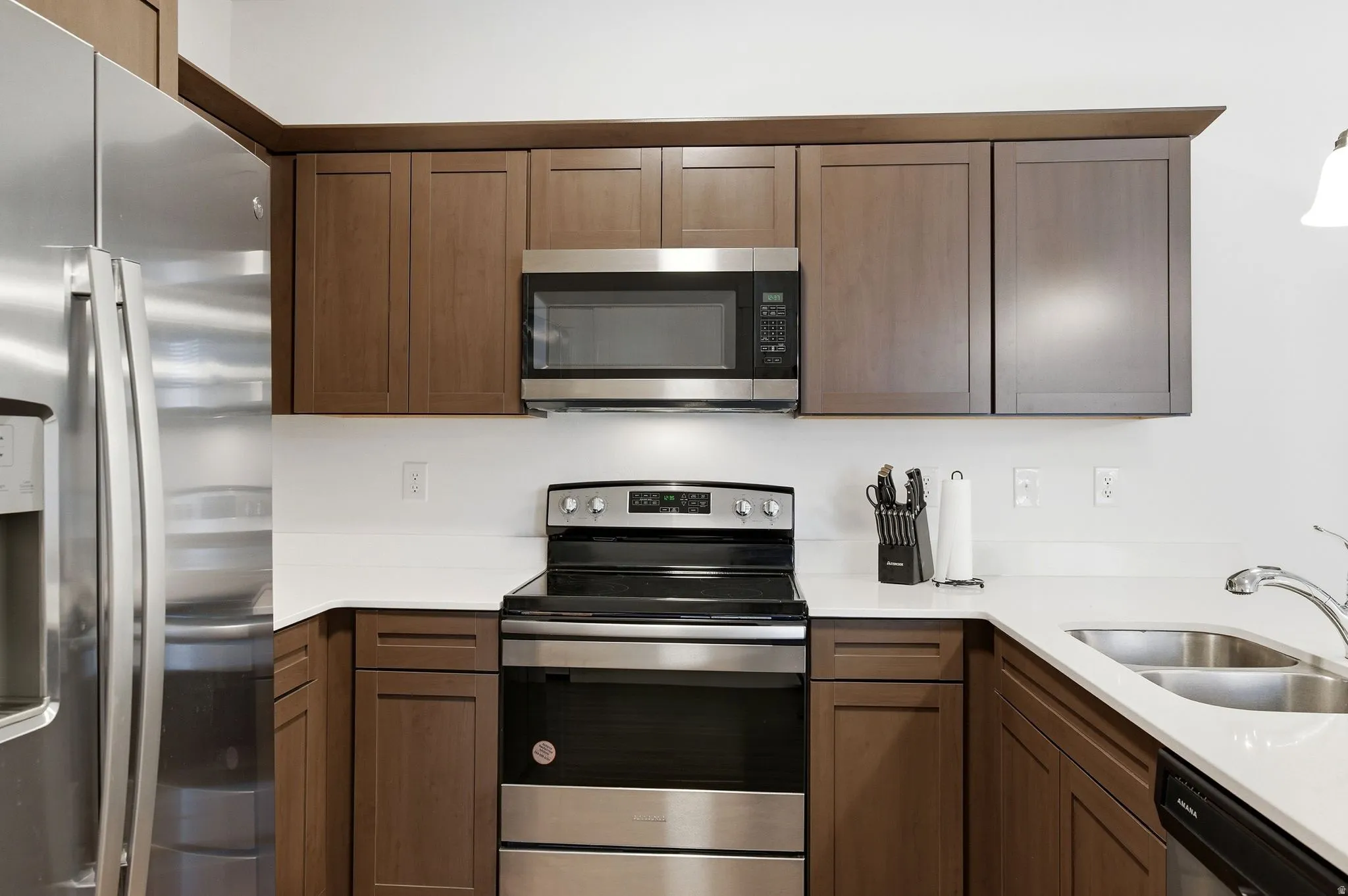 Kitchen with stainless steel appliances and light stone countertops