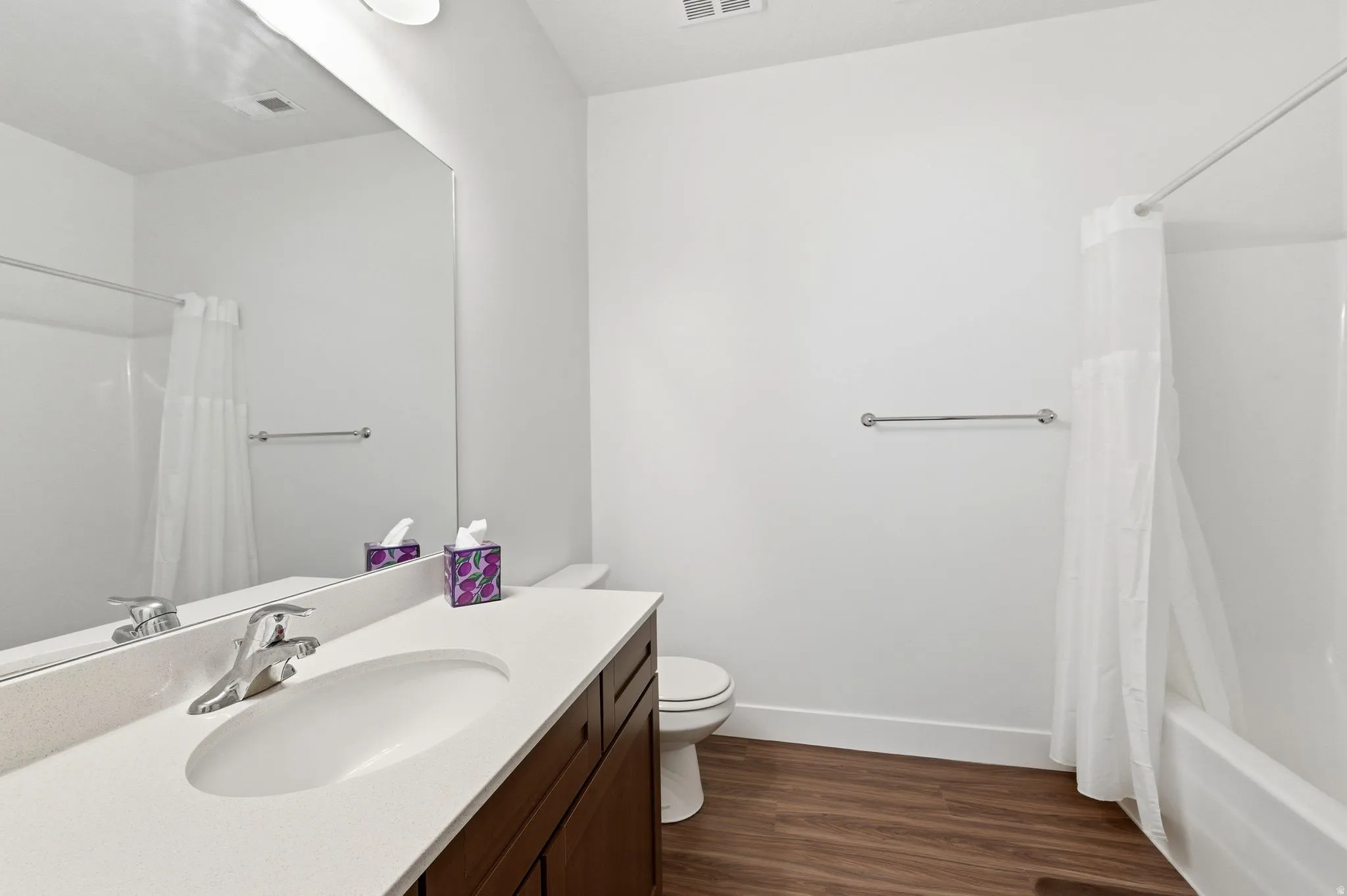 Full bath with vanity, dark wood finished floors, and shower / tub combo