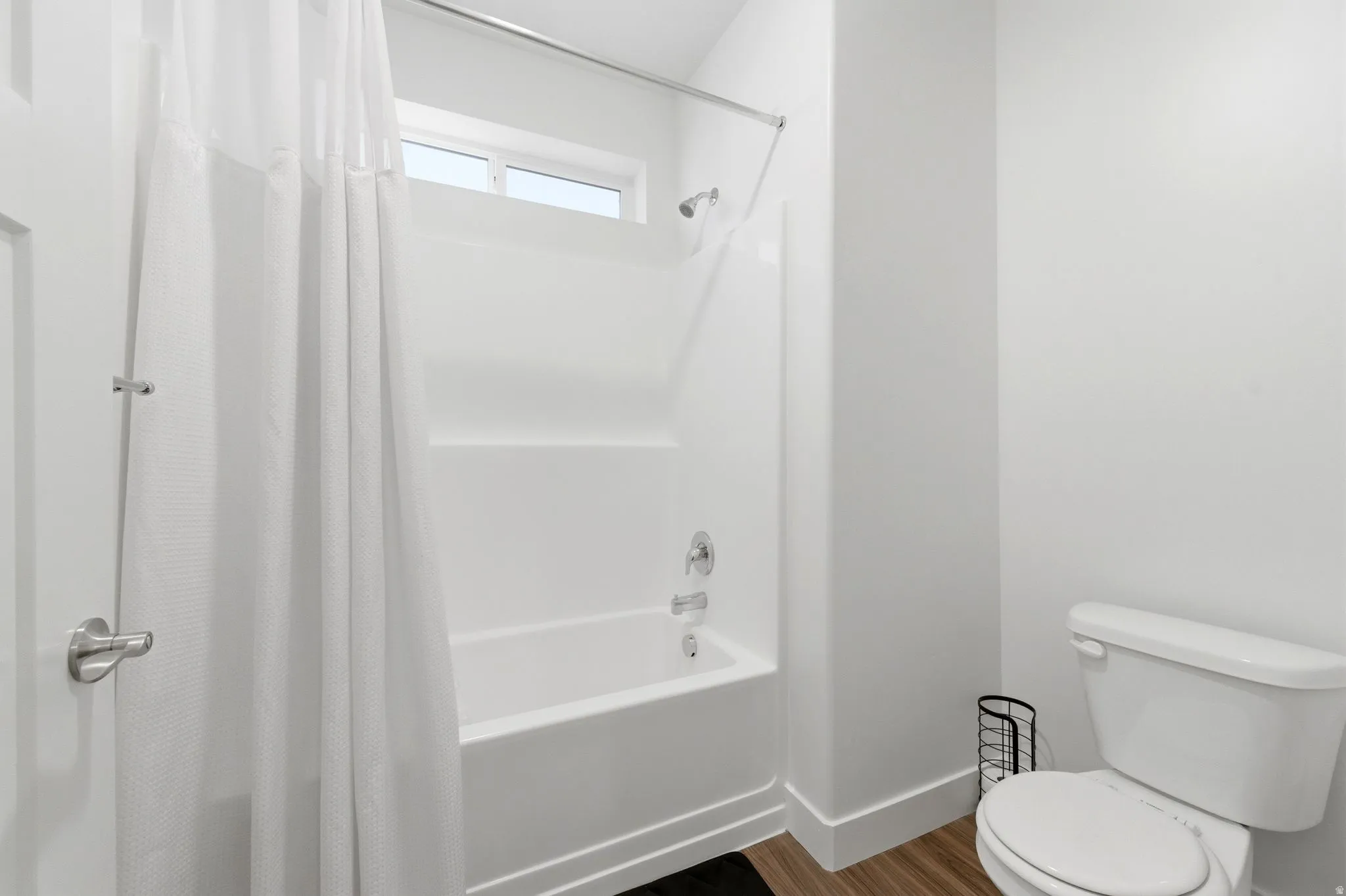 Full bathroom with shower / tub combo and dark wood-type flooring