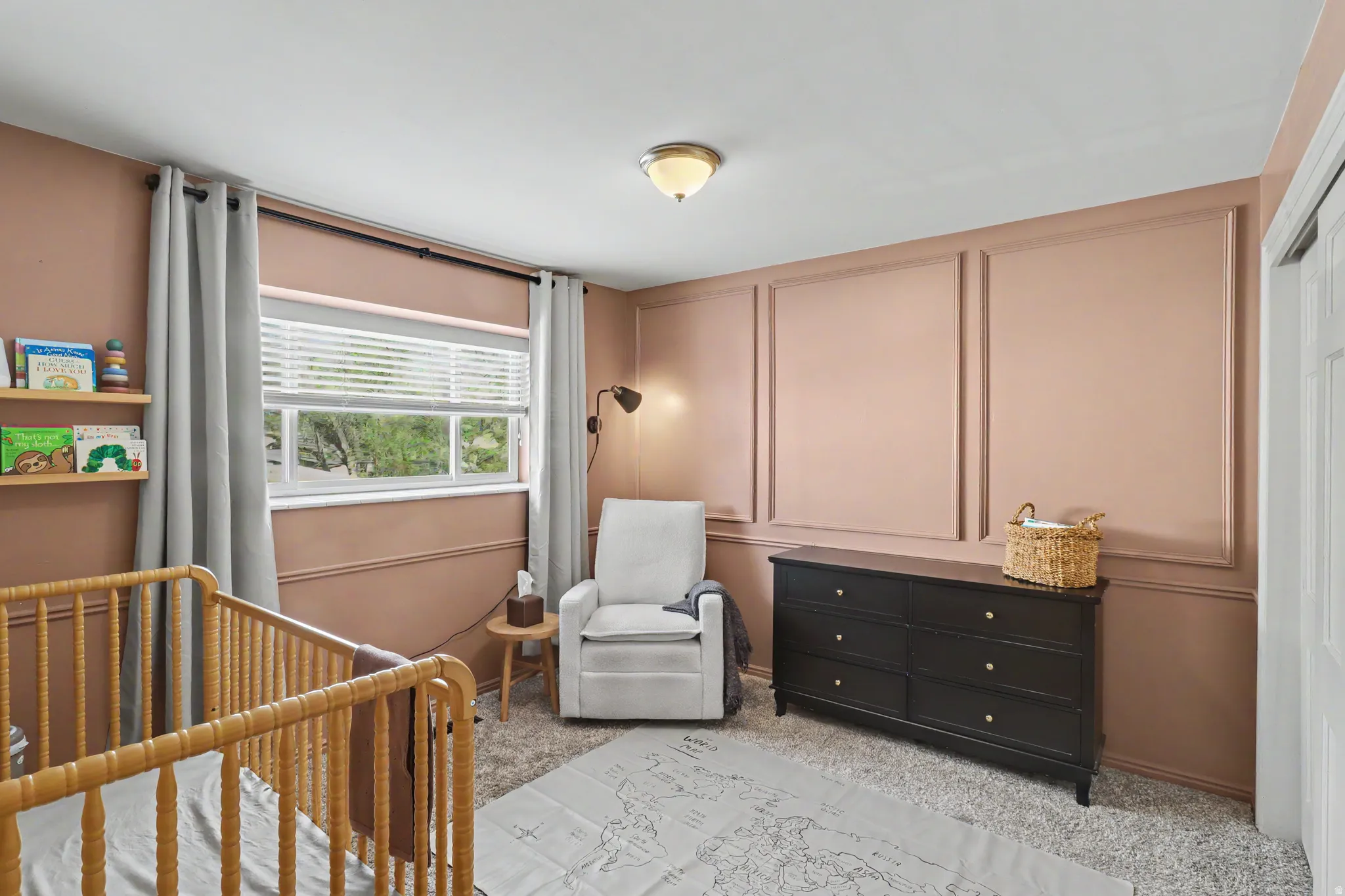 Bedroom featuring a decorative wall, light colored carpet, and a nursery area
