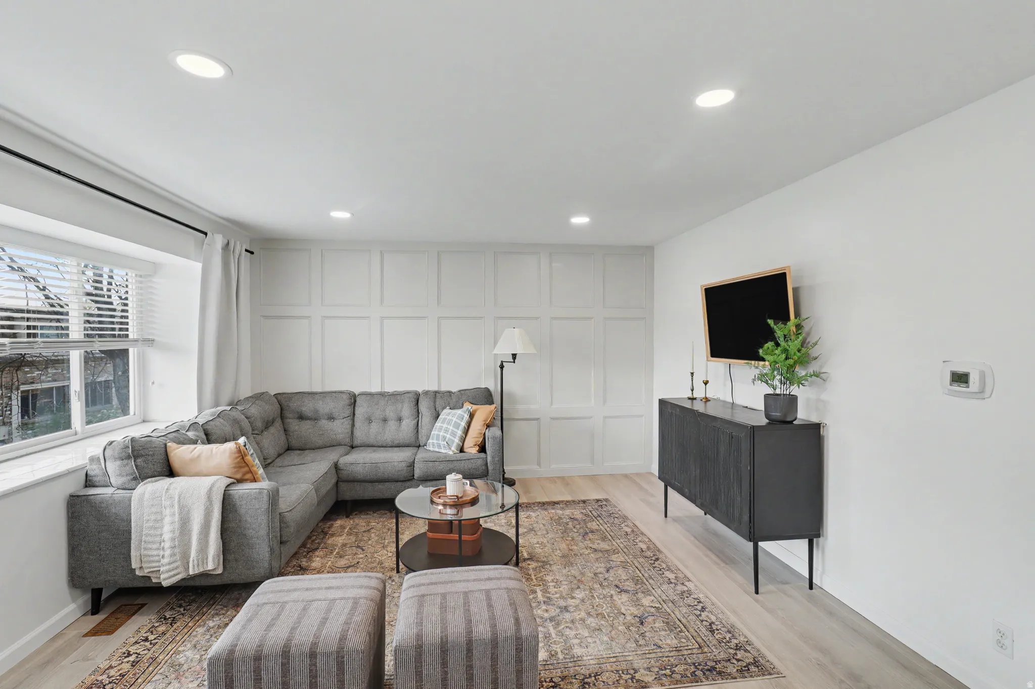 Living room with light wood-style floors, recessed lighting, and a decorative wall