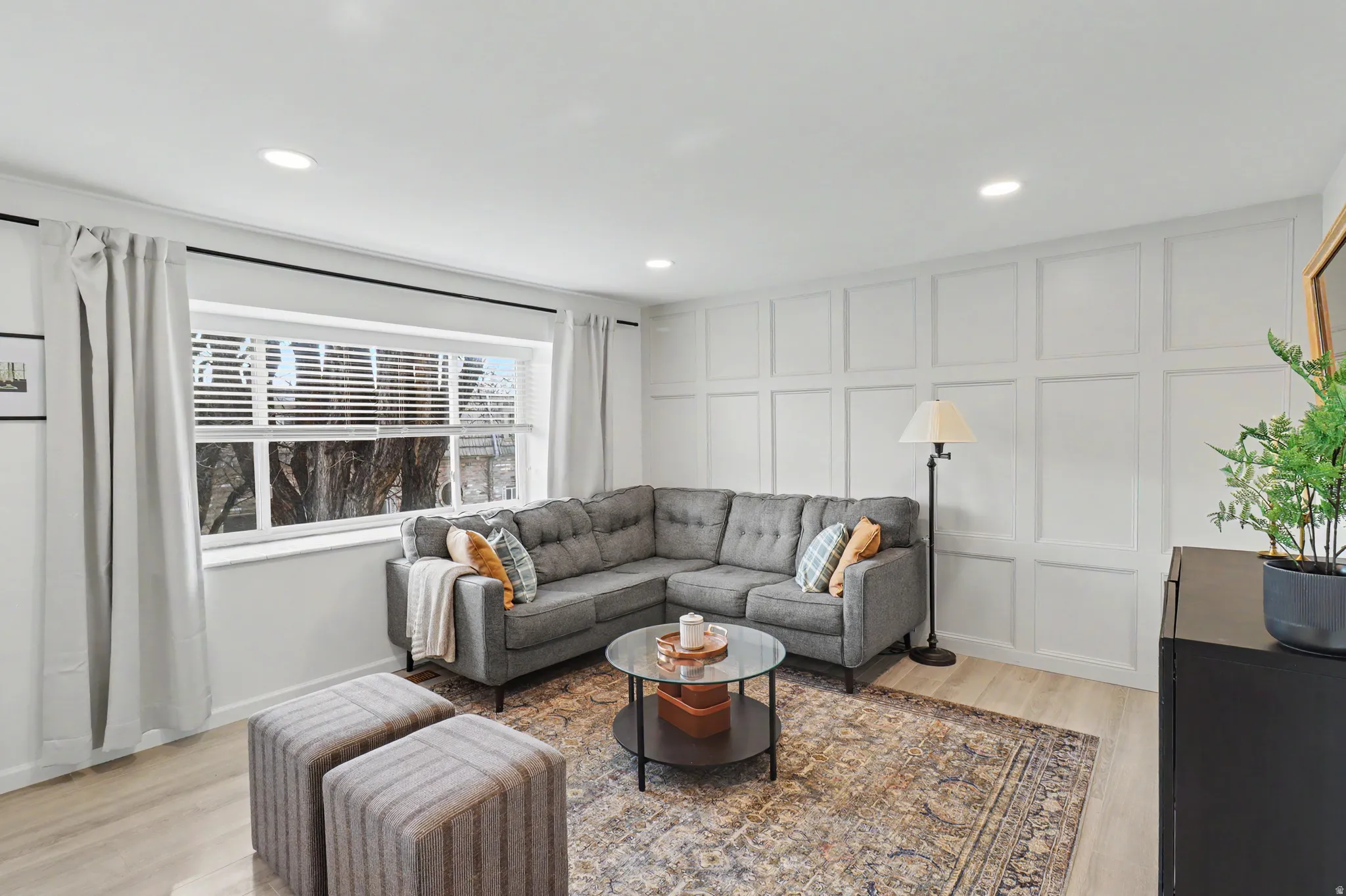 Living area featuring a decorative wall, light wood-type flooring, and recessed lighting