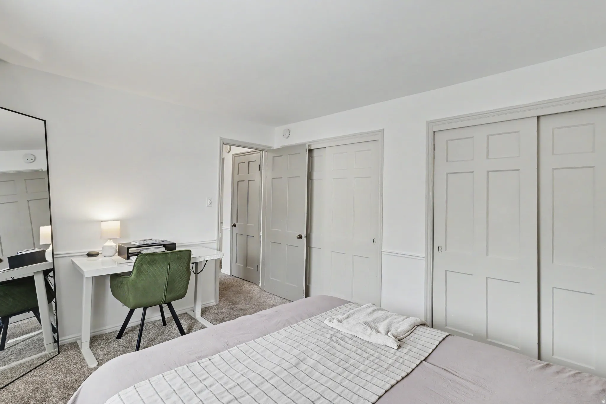 Bedroom featuring light colored carpet, two closets, and an office area