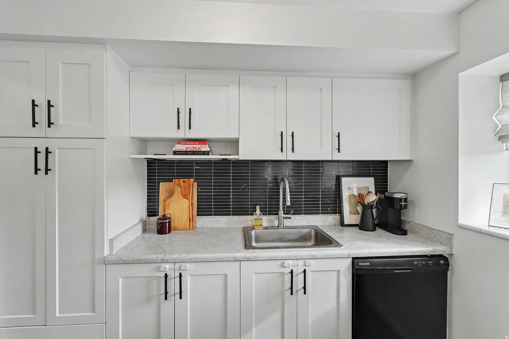 Kitchen with white cabinetry, dishwasher, light countertops, and backsplash