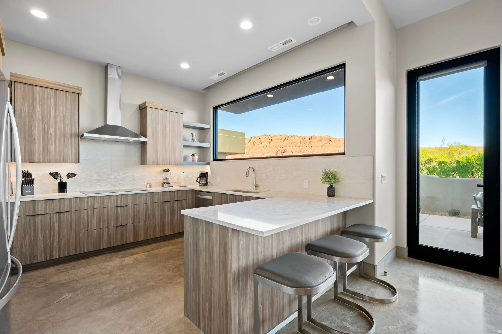 Kitchen featuring modern cabinets, concrete flooring, a breakfast bar area, a peninsula, and backsplash