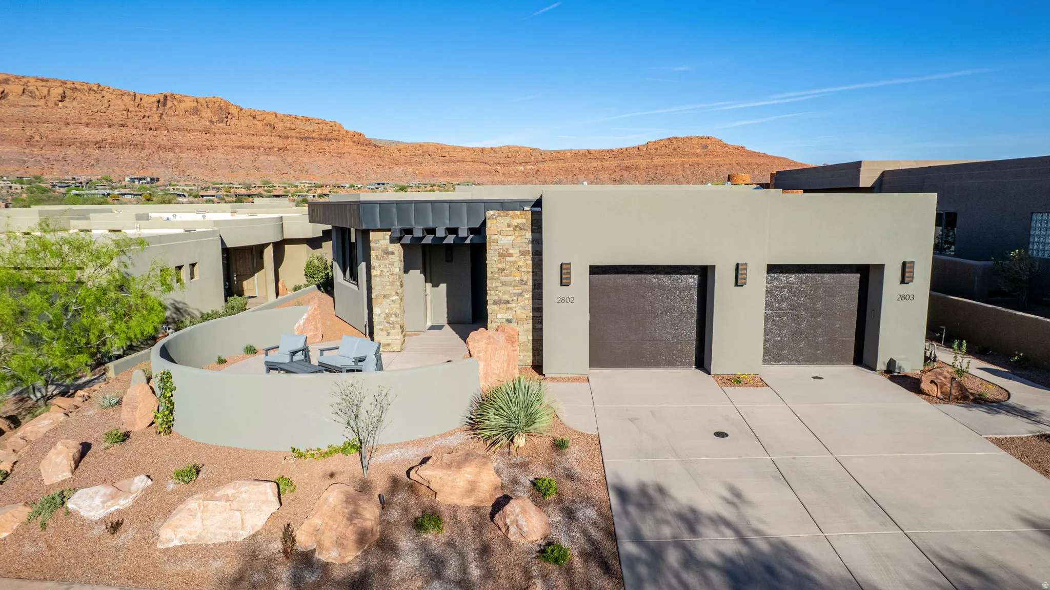 View of front of property with a mountain view, stone siding, an attached garage, concrete driveway, and stucco siding